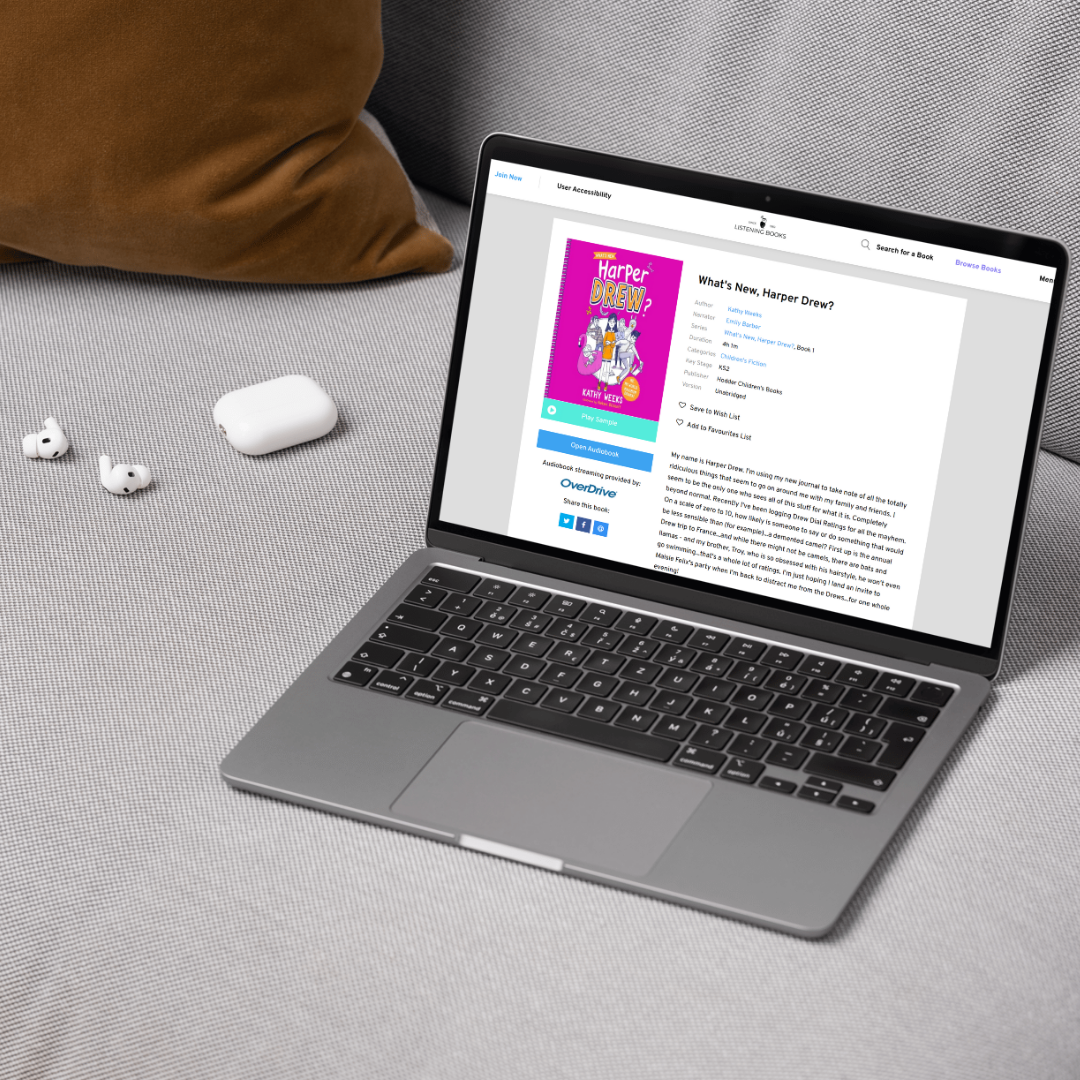 Laptop with Listening Books website, sat next to white earphones.